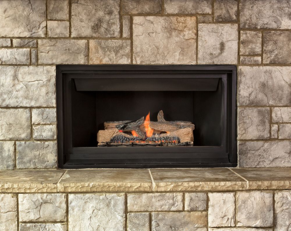 A burning natural gas fireplace with a stone wall