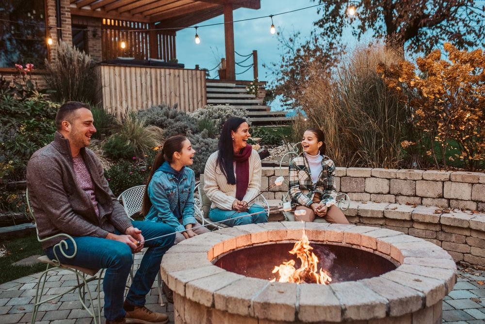 Family roasting marshmallows over fire pit