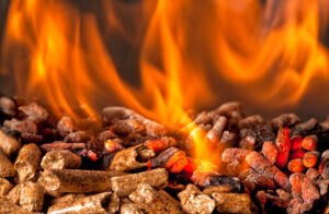 A close up image of wood pellets over an open fire inside of a pellet stove.