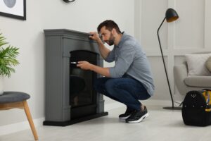 A man uses a screwdriver to install an electric fireplace