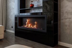 A closeup of a home's mantle with a gas fireplace burning