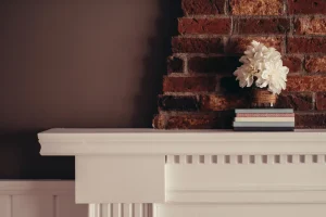 A fireplace mantle with a stack of books and white flowers on top